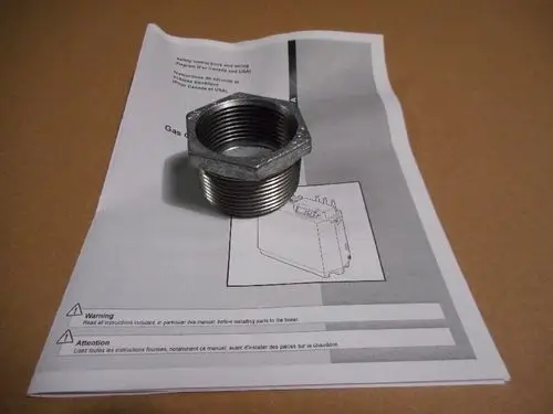 Muffe aus Metall, die auf einer Anleitung für Remeha-Produkte liegt. Die Anleitung enthält Warnhinweise und technische Informationen.